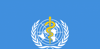 Flag of the World Health Organization (WHO) with a light blue background, the United Nations emblem, and a Rod of Asclepius in the center. Σημαία του Παγκόσμιου Οργανισμού Υγείας (ΠΟΥ) με γαλάζιο φόντο, το έμβλημα του ΟΗΕ και ένα ραβδί του Ασκληπιού στο κέντρο. (GR)