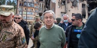 Ο Γενικός Γραμματέας του ΟΗΕ Αντόνιο Γκουτέρες σε επίσκεψή του στο Ιρπίν στην Ουκρανία τον Απρίλιο του 2022, περιτριγυρισμένος από Ουκρανούς αξιωματικούς και στελέχη του ΟΗΕ, ενώ στο βάθος διακρίνονται χαλάσματα πολυκατοικίας.
