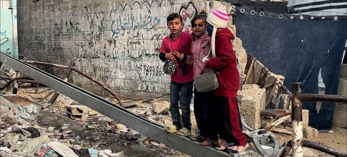 Children in Gaza stand on debris from a destroyed building. Παιδιά στη Γάζα στέκονται πάνω σε ερείπια από ένα κατεστραμμένο κτίριο.