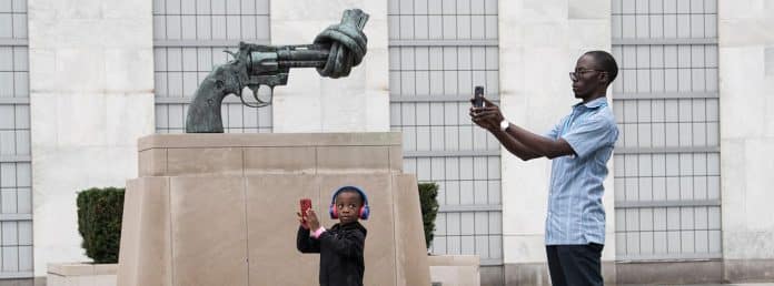 Olumuyiwa Ogunbamow and his son Adefie (5), visiting from Nigeria, take photos in front of the “Non-Violence” (or “Knotted Gun”) sculpture. Photo:UN Photo/Kim Haughton
