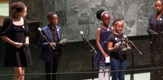 Photo of a woman and 4 children standing at the podium in the GA hall as one of them speaks © UN Photo/Eskinder Debebe