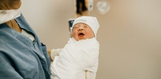 Newborn baby held by midwife
