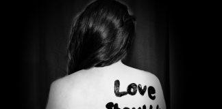 "Love should not hurt" message on woman's back | via Sydney Sims on Unsplash