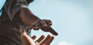 Two people's hands trying to reach each other