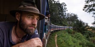 A man looking out from a train window in an exotic destination