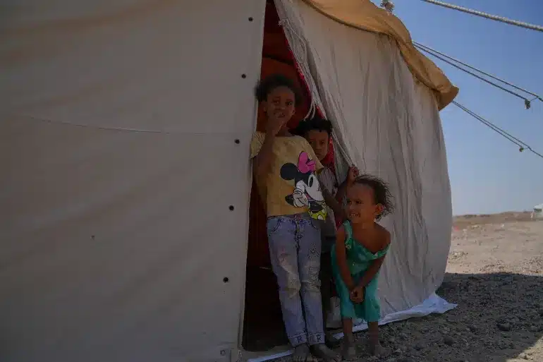 Children in front of their tent in AlFirdos displacement camp around Aden. Tens of thousands of children have been internally displaced after escalation in violence on the western coast of Yemen early September 2026