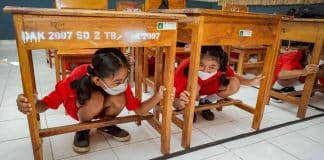 School girls hiding under a table. © UNDRR/Antoine Tardy