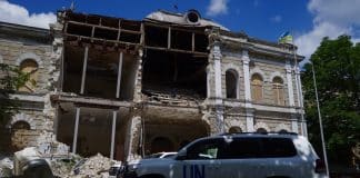War damaged building with a car that says UN