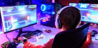 Young teenager with a headset gaming on multiple screens