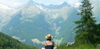 PErson sitting in front of a mountain in the distance. Scenic photo evoking sustainable tourism