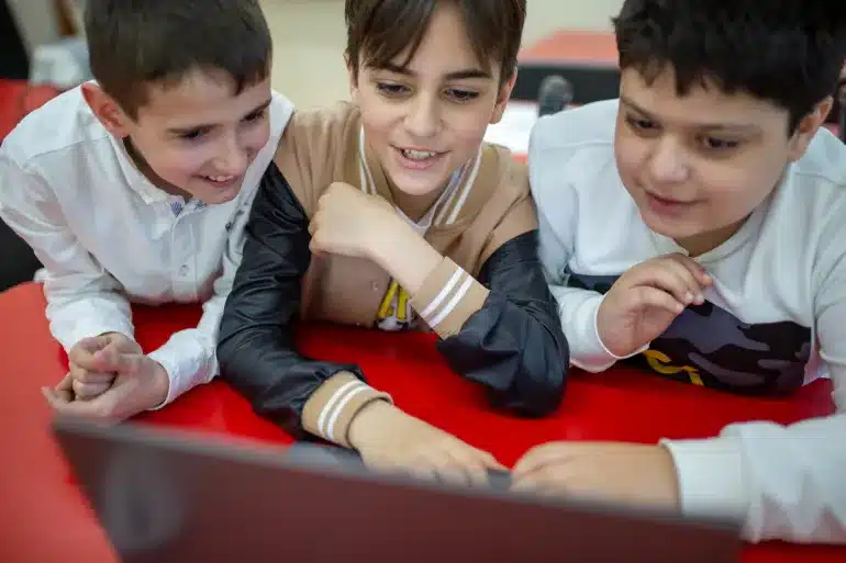 Three children gathered around a computer