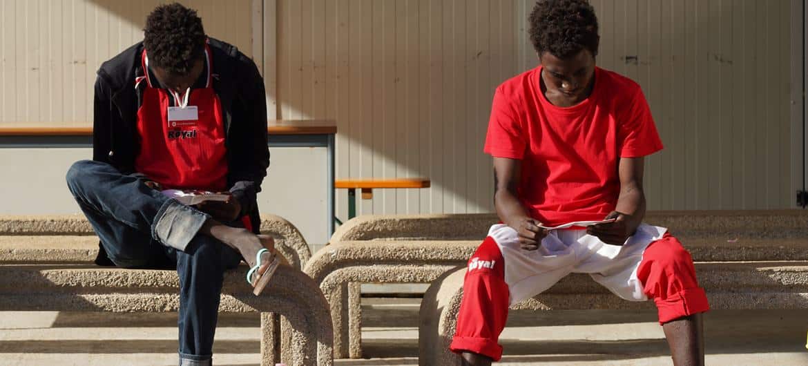 Unaccompanied teenagers read informational brochures in Lampedusa, Italy, after crossing the Mediterranean, most often via Mali or Niger and Libya. © UNICEF/Niccolò Corti