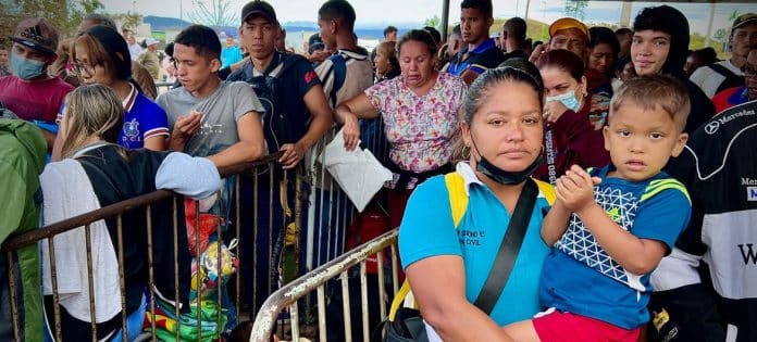 Madre con hijo-migrantes-venezolanos hacen fila-Pacaraima- frontera Brasil