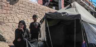 Siirretty perhe istuu telttansa ulkopuolella Gazassa. Kuva: © UNICEF/Mohammed Nateel