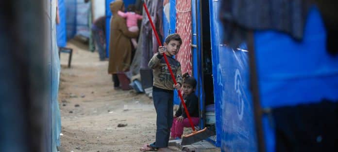 Lapsi siivoaa väliaikaista suojaa Gazassa. © UNRWA