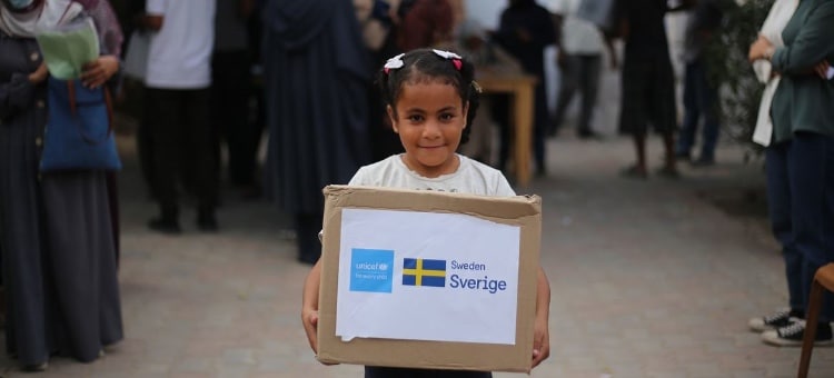 Lapsi Gazassa kantaa laatikollista talvivaatteita. © UNICEF / Eyad El Baba