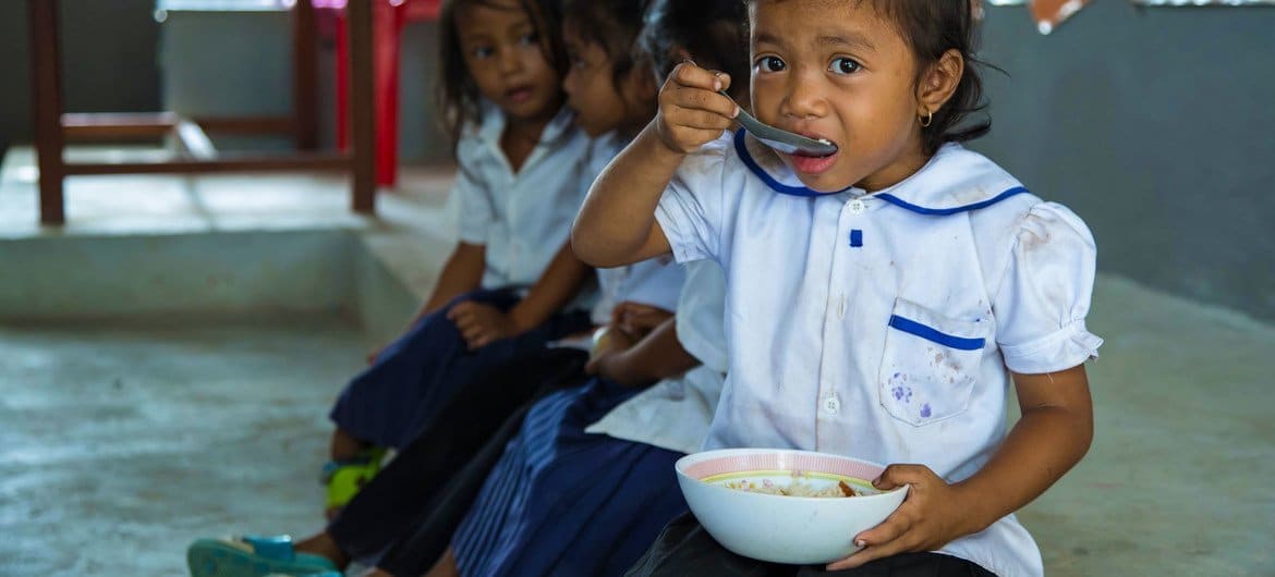 Nuori tyttö syö aterian koulussa ennen koulun alkua Kambodžassa. Kuva: © UNICEF/Bona Khoy
