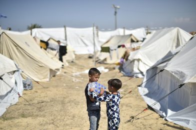 Yamen 7 ára og bróðir hans Yazan, 4 ára hjalda á vatnsflöskum frá UNICEF í flóttamannabúðum UNRWA í Khan Yunis í suðurhluta Gasa.