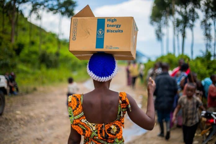 Kona með kassa frá WFP með orkuríku kexi. Matvælum var komið til bágstaddra eftir flóði í Suður Kivu í Lýðveldinu Kongó. Mynd: WFP/FSC/Martin Lukongo