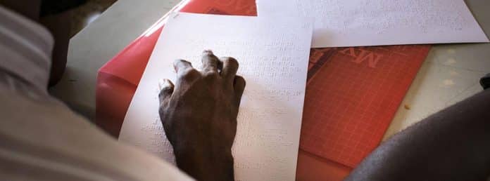 Kjósandi í Sierra leone með kjörseðil á blindralestri í kosningum 2018.