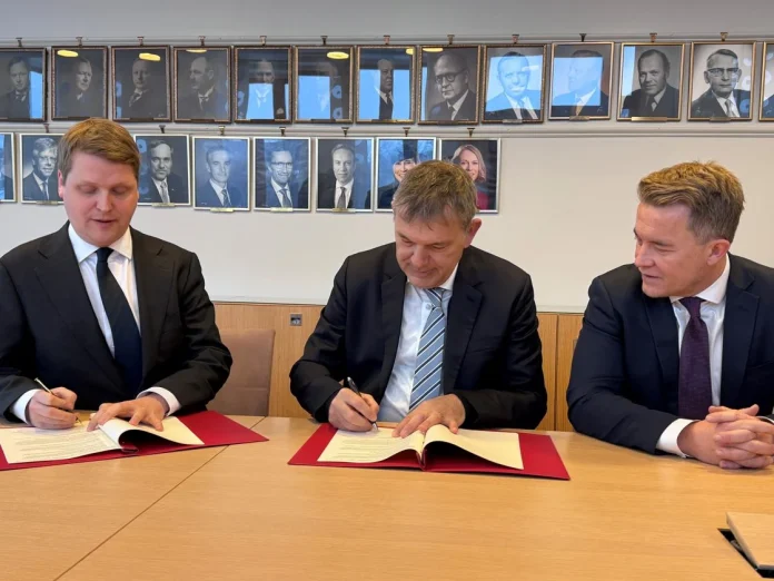 Åsmund Aukrust og Philippe Lazzarini undirrita samninginn. Andreas Motzfeldt Kravik til hægri.