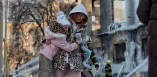 Mæðgur ganga fram hjá illa skemmdri verksmiðju í Kyiv eftir loftárás.
