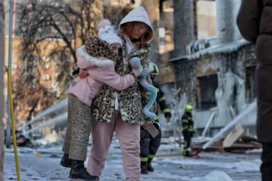 Mæðgur ganga fram hjá illa skemmdri verksmiðju í Kyiv eftir loftárás.