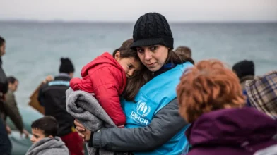 Starfsmaður UNHCR heldur á ungu flóttabarni vöfðu í teppi eftir að bátur þeirra lenti á grísku eyjunni Lesbos. Mynd: © UNHCR/Hereward Holland