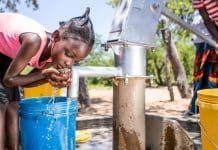 Una giovane ragazza raccoglie dell’acqua da un pozzo