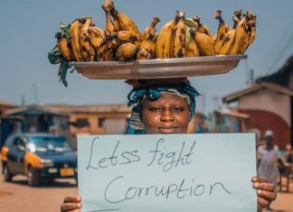 Manifestante in Ghana mostra cartello contro la corruzione