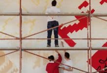 In foto, dei giovani dipingono un muro