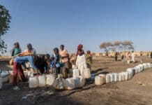 Adulti e bambini sfollati fanno la fila per raccogliere l'acqua da una pompa alimentata a energia solare installata dal UNDP nel campo profughi di Abu Al-Naja, nella città di Gedaref, nello Stato di Gedaref, a circa 400 chilometri a sud-est di Khartoum.