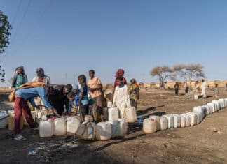 Adulti e bambini sfollati fanno la fila per raccogliere l'acqua da una pompa alimentata a energia solare installata dal UNDP nel campo profughi di Abu Al-Naja, nella città di Gedaref, nello Stato di Gedaref, a circa 400 chilometri a sud-est di Khartoum.