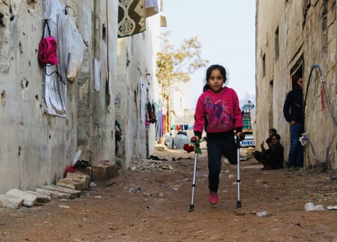 Flicka med ett ben på kryckor i Syrien