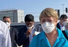 En kvinna i mask i förgrunden, en man i bakgrunden