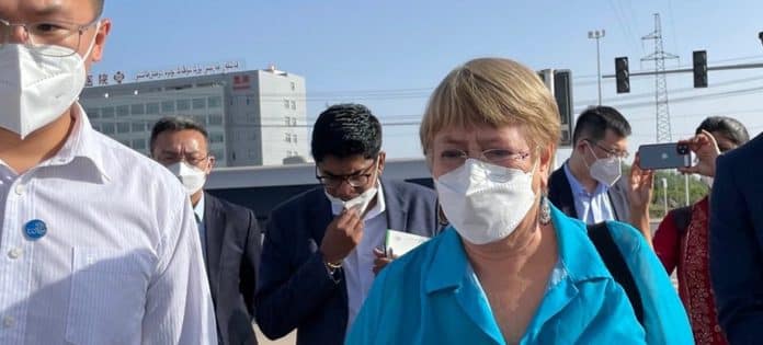 En kvinna i mask i förgrunden, en man i bakgrunden