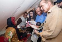 Fyra människor som samlats kring en baby i en primitiv miljö. Babyn hålls av Antonio Guterres.