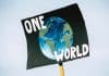 En skylt med texten one world och en bild på vår planet