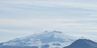 En glaciär i bakgrunden och mark i förgrunden.