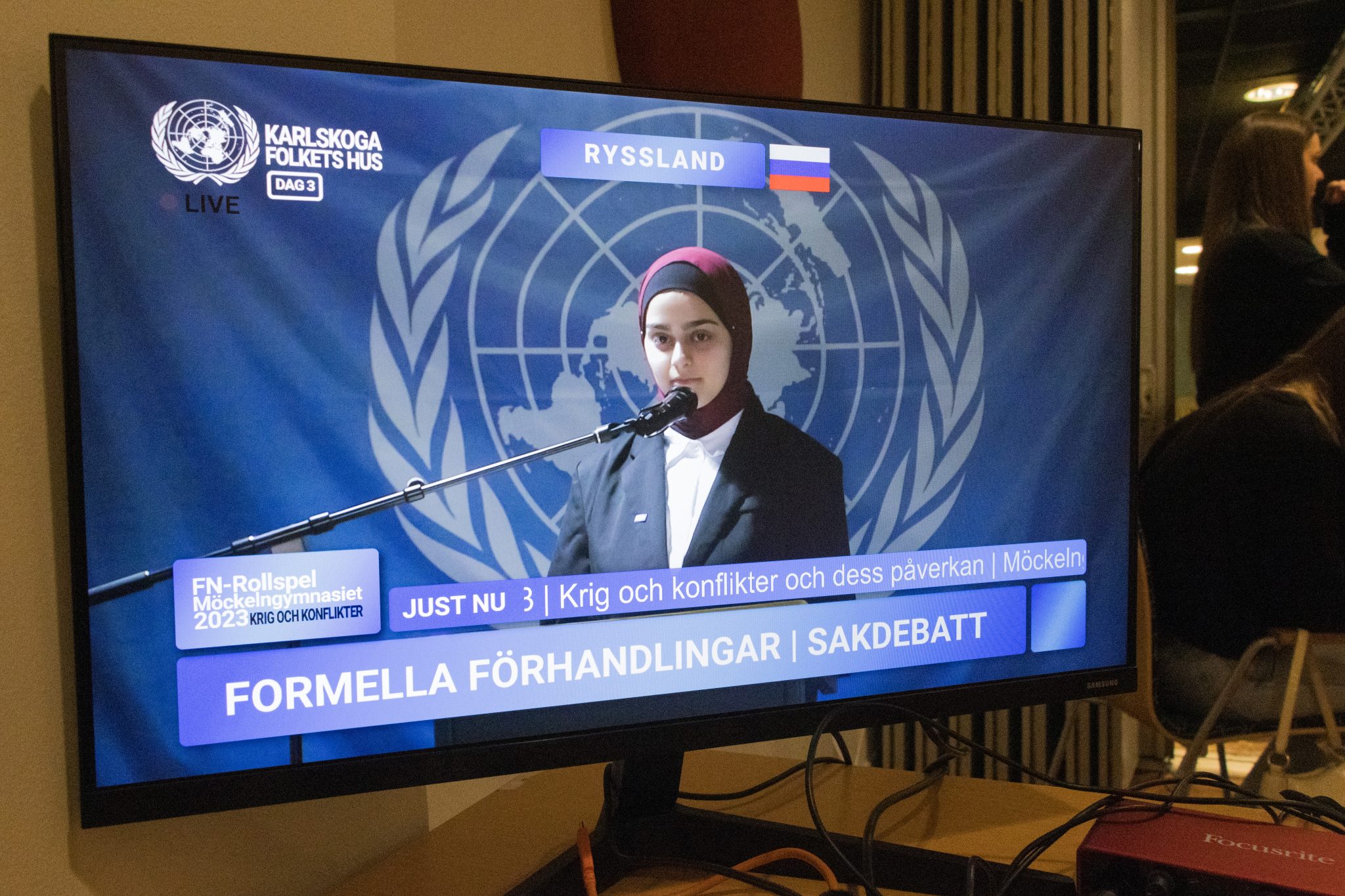 En skärm med en kvinna som pratar i mikrofon