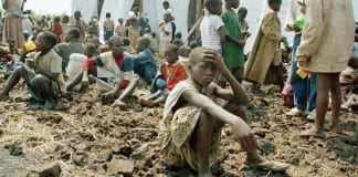 Barn som sitter på jordig mark i anspråkslösa förhållanden