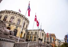 En byggnad i bakgrunden och nordiska flaggor i förgrunden