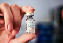 En liten flaska vaccin i en hand