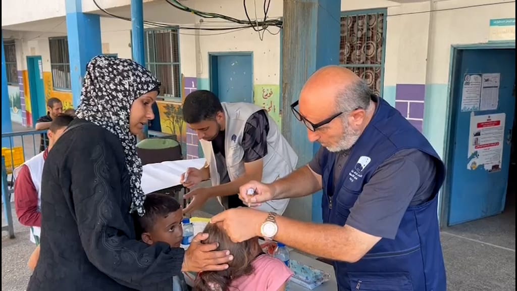 En person som ger vaccin till barn i kö