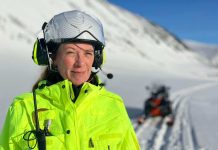 En kvinna i hjälm med istoppar i bakgrunden