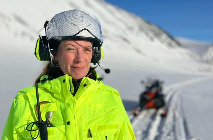 En kvinna i hjälm med istoppar i bakgrunden