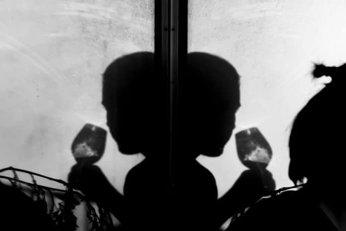 Silhuetten av en person med ett glas i handen