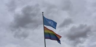 Två hissade flaggor, en för FN och en regnbågsflagga