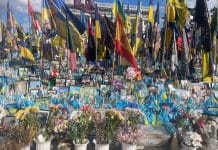 En offentlig minnesplats fylld med blommor och flaggor