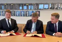 Tre män som undertecknar ett dokument
